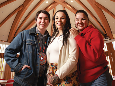 Three members of the 91 Indigenous community smiling inside the Indigenous Sharing and Learning Centre 